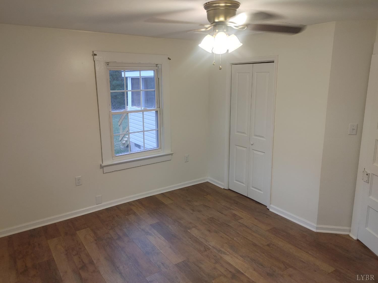 7143 Abilene Road Farmville, VA 23901 - Photo 19 of 38 an empty room with wooden floor chandelier fan and windows
