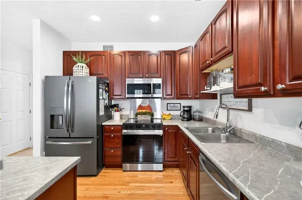 a kitchen with stainless steel appliances granite countertop a refrigerator a sink dishwasher a stove top oven and a center island