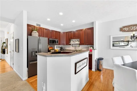 a kitchen with stainless steel appliances granite countertop a refrigerator a stove a sink dishwasher and a refrigerator with wooden floor