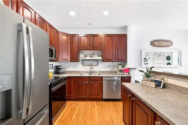a kitchen with stainless steel appliances granite countertop a sink stove refrigerator and cabinets