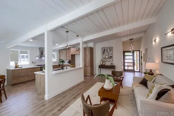 a large living room with stainless steel appliances furniture a couch and a kitchen view