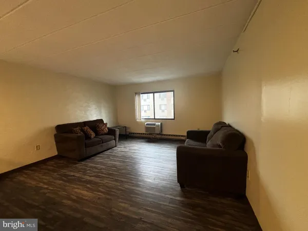 a living room with couches and a flat screen tv with wooden floor