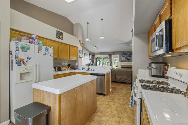 a kitchen with stainless steel appliances a refrigerator a sink a stove top oven a chimney and a center island