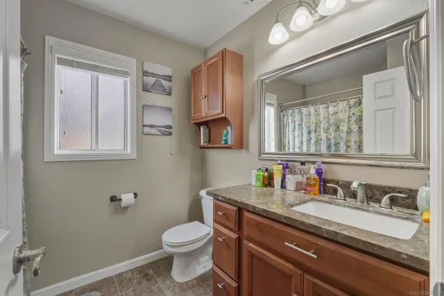 a bathroom with a granite countertop toilet sink and mirror