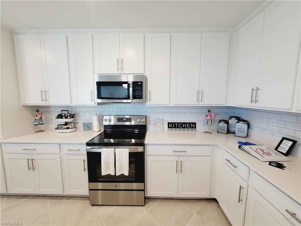 43981 Boardwalk Loop, Unit 2232 Punta Gorda, FL 33982 - Photo 2 of 34 Kitchen with tasteful backsplash, white cabinetry, appliances with stainless steel finishes, and light tile patterned floors