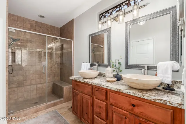a bathroom with double vanity sinks and a glass door shower