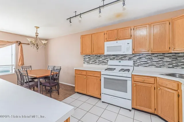a kitchen with stainless steel appliances granite countertop a stove a sink dishwasher a dining table and chairs with wooden floor