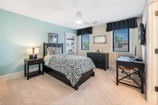 a bedroom with a bed table chair and a window