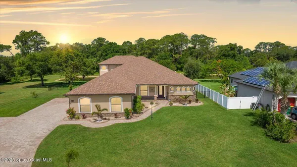 a aerial view of a house with swimming pool garden and trees