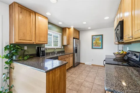 a kitchen with granite countertop a sink a stove cabinets and counter space