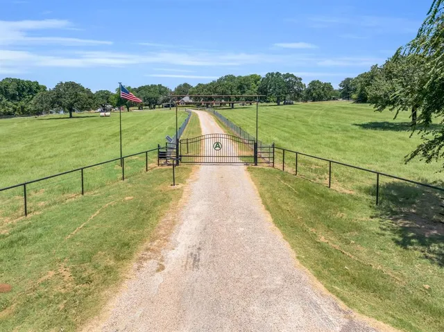 an aerial view of a residential houses with outdoor space and trees all around