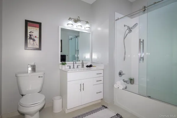 a bathroom with a toilet sink vanity granite and shower
