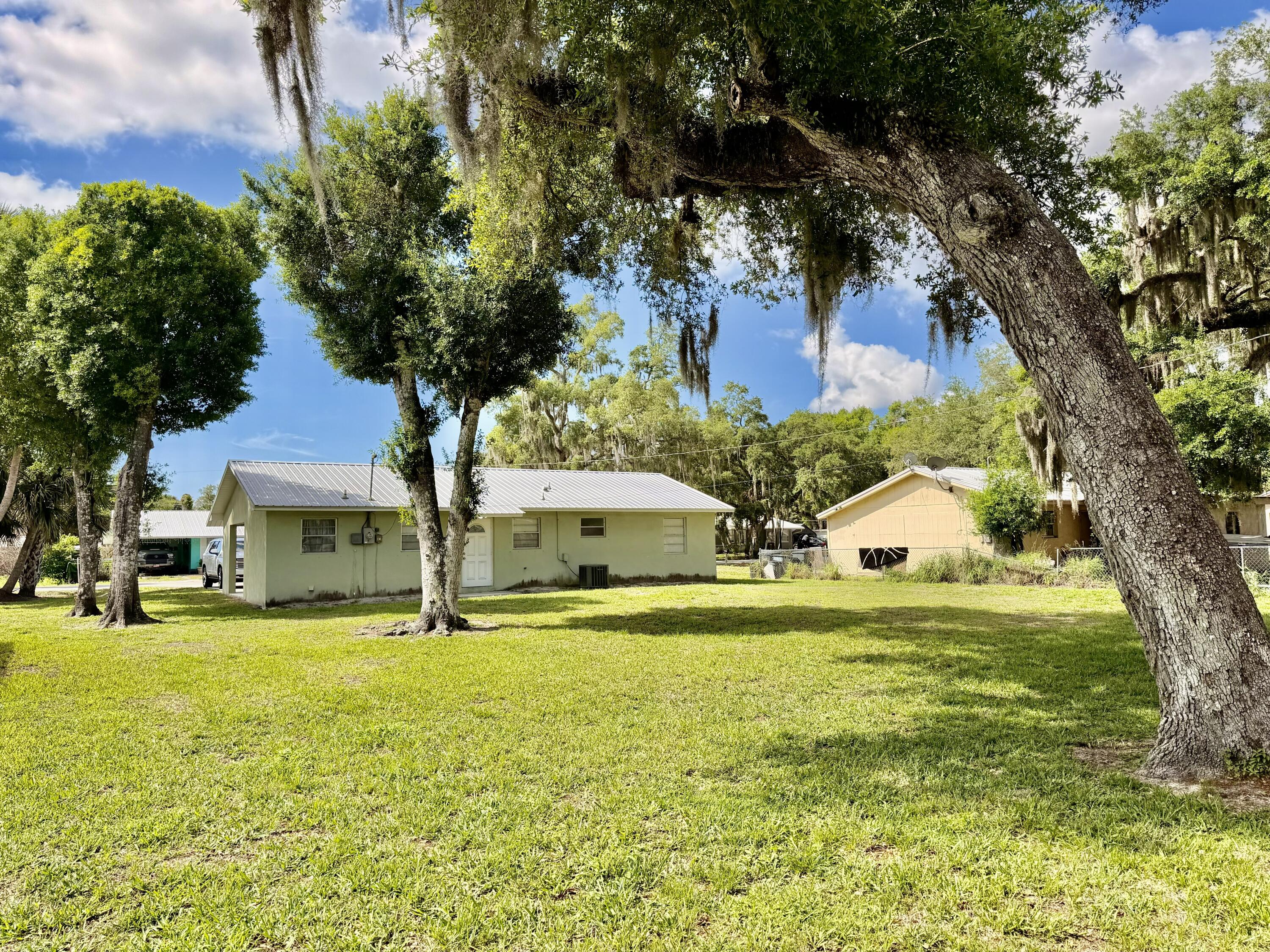 3283 Southwest 20th Street Okeechobee, FL 34974 - Photo 2 of 19 a yellow house with a big yard and large trees