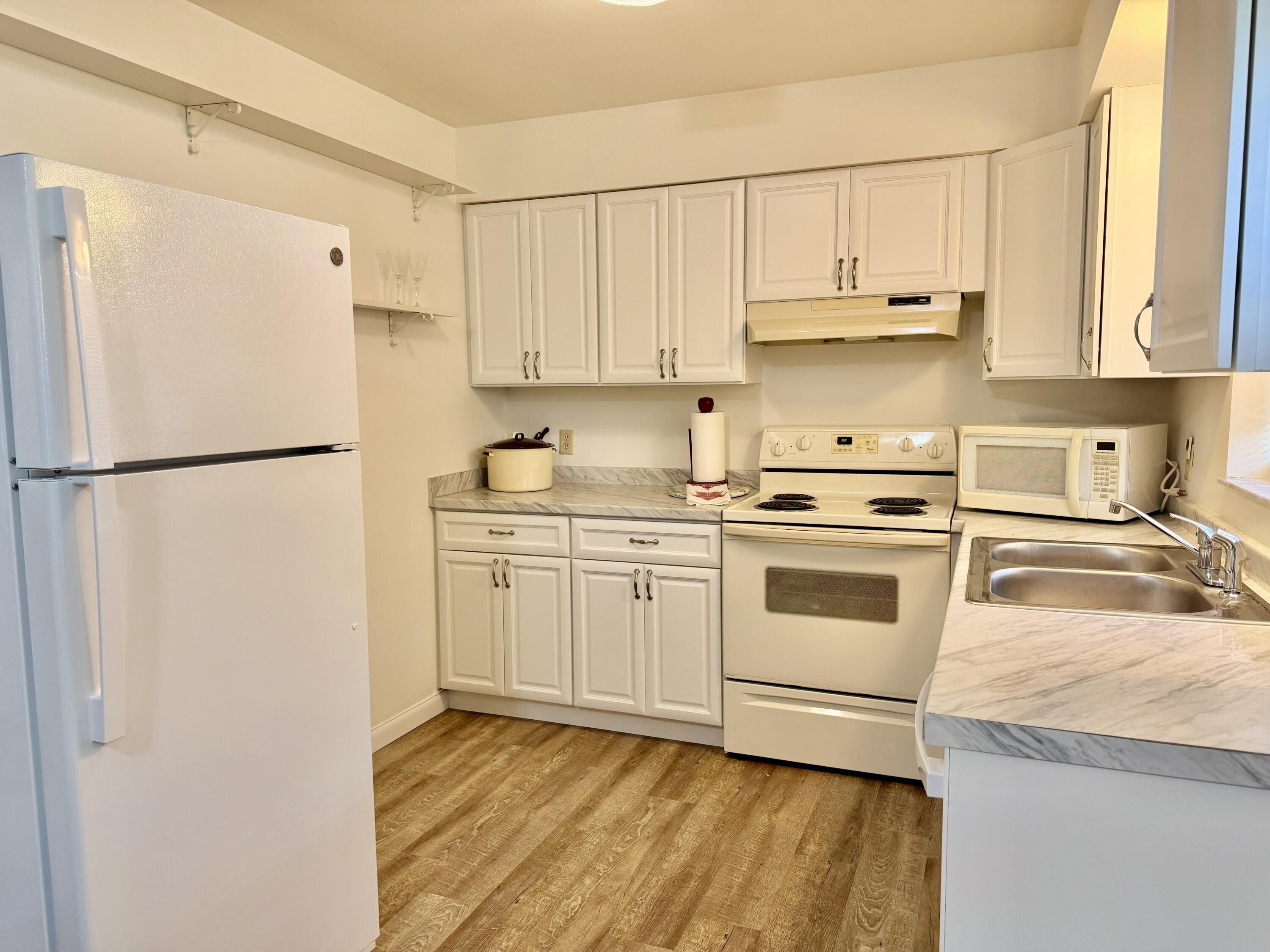 3283 Southwest 20th Street Okeechobee, FL 34974 - Photo 6 of 19 a kitchen with white cabinets and white appliances