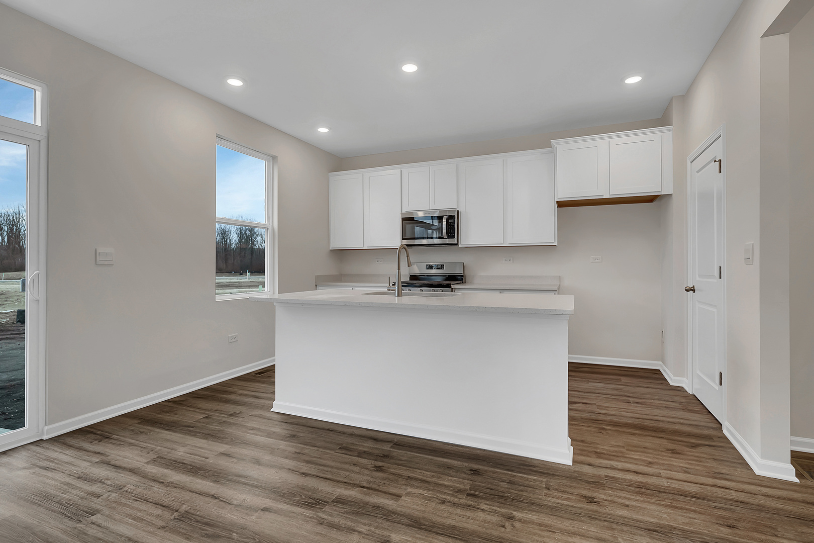 6720 Applegate Drive Plainfield, IL 60586 - Photo 7 of 17 a kitchen with wooden floors white cabinets and stainless steel appliances