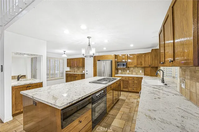 a view of a kitchen with kitchen island a sink a counter top space and stainless steel appliances