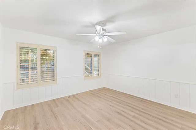 an empty room with a window and a ceiling fan