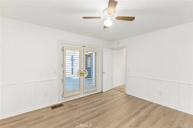 an empty room with wooden floor fan and windows
