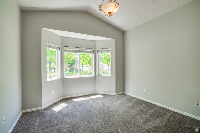 1433 Forge Way Draper, UT 84020 - Photo 18 of 29 Bay window with multiple panes, vaulted ceiling, neutral wall color, and textured carpeting, complemented by a decorative ceiling fixture
