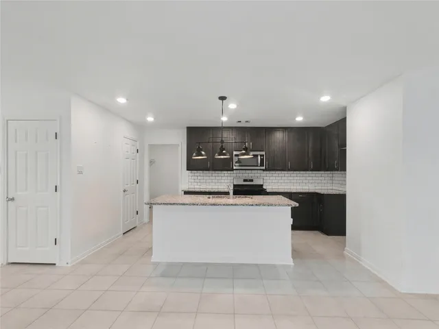 a large white kitchen with a stove a sink a microwave and island