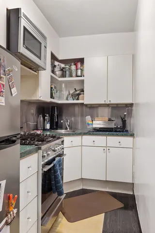 a kitchen with stainless steel appliances granite countertop a stove a sink and a microwave
