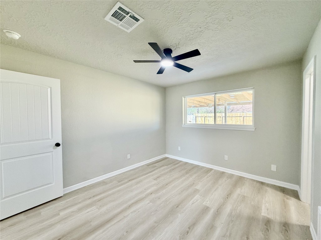 1710 Beaver Bend Road Houston, TX 77088 - Photo 22 of 32 an empty room with wooden floor ceiling fan and windows
