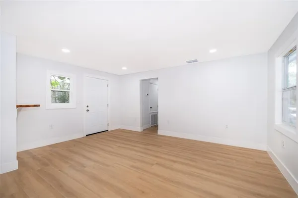 a view of an empty room with wooden floor and a window