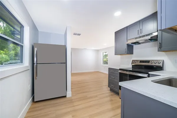 a kitchen with a refrigerator stove and wooden floor
