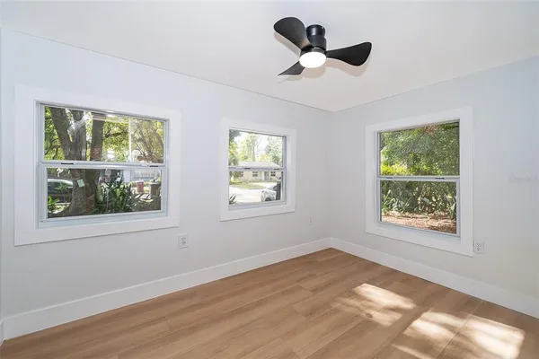 a view of an empty room with a window and wooden floor