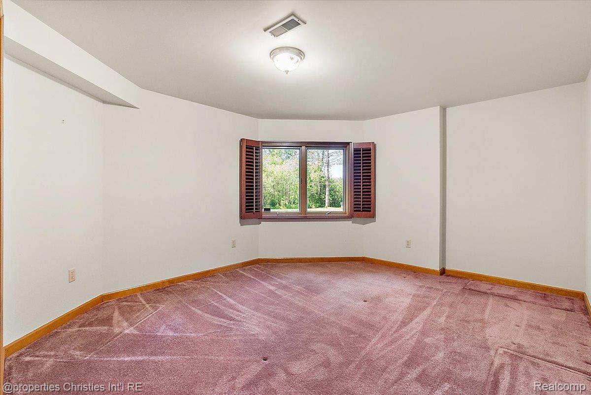 6175 Tripp Road Holly, MI 48442 - Photo 31 of 63 Room featuring a bay window with wooden shutters, recessed ceiling beam, overhead light fixture, and wall-to-wall carpeting