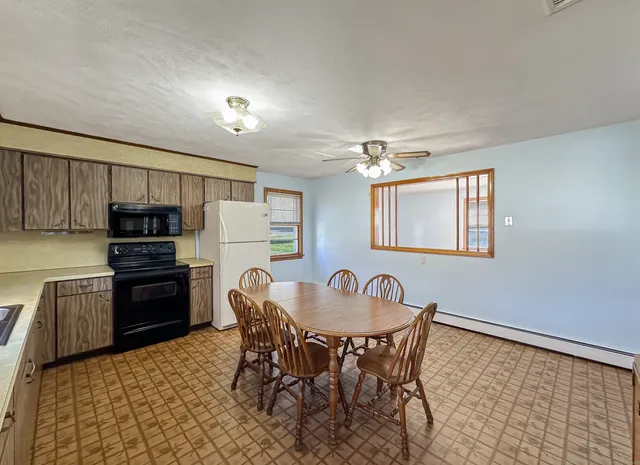 a kitchen with granite countertop a dining table chairs and refrigerator