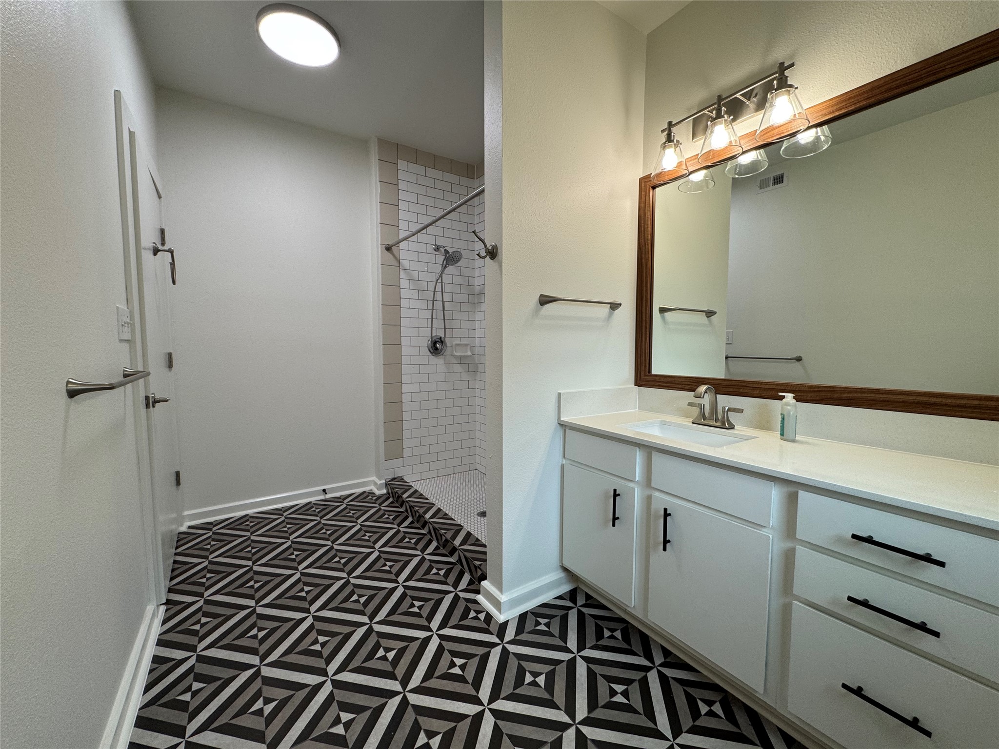 1201 Grove Boulevard, Unit 1701 Austin, TX 78741 - Photo 7 of 10 a bathroom with a double vanity sink a mirror and a shower