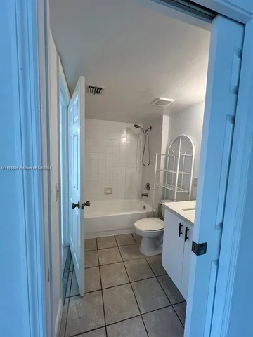a bathroom with a granite countertop bathtub shower sink mirror vanity and toilet