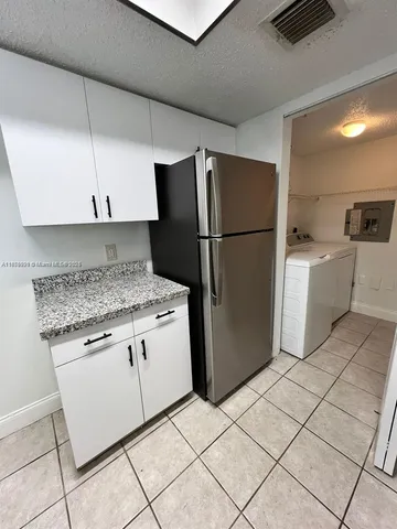 a kitchen with a refrigerator a stove top oven and cabinets