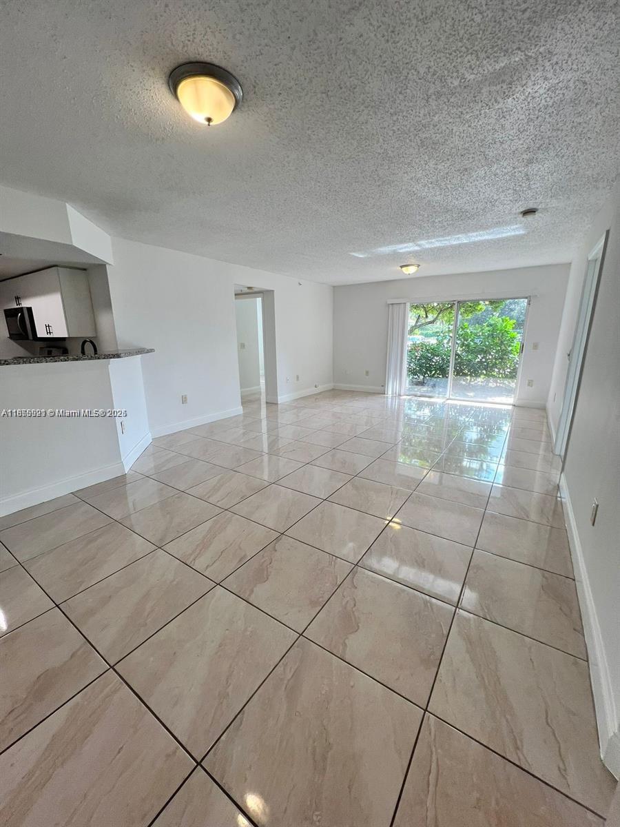 5065 Wiles Road, Unit 103 Coconut Creek, FL 33073 - Photo 3 of 20 a view of a livingroom with wooden floor and a window