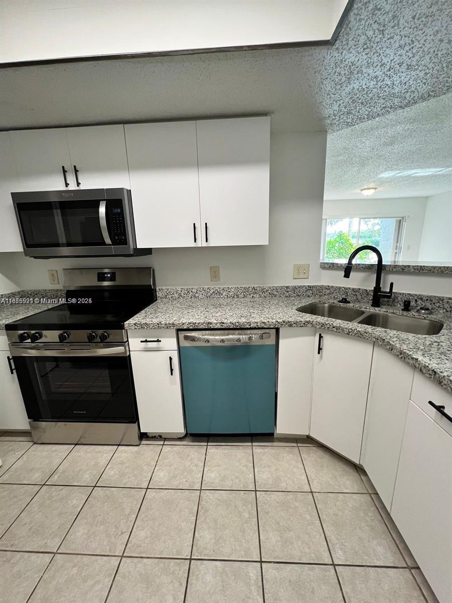 5065 Wiles Road, Unit 103 Coconut Creek, FL 33073 - Photo 6 of 20 a kitchen with a sink a stove and cabinets