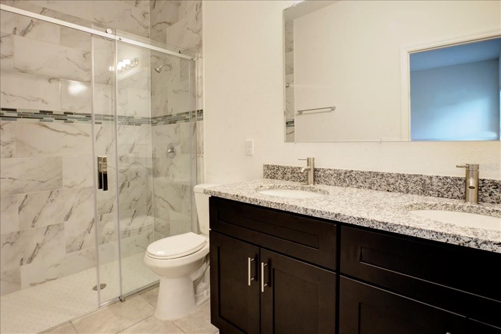 6952 Southwest 152nd Street Ocala, FL 34473 - Photo 10 of 25 a bathroom with a granite countertop sink toilet a mirror and shower