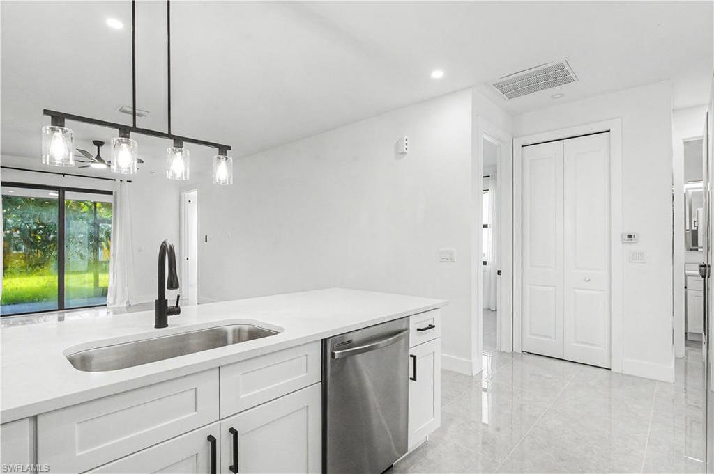 2239 Armour Road Lehigh Acres, FL 33973 - Photo 6 of 24 Modern kitchen featuring clean-lined white cabinetry, a stainless steel undermount sink with matte black faucet, and a quartz countertop with waterfall edge detail