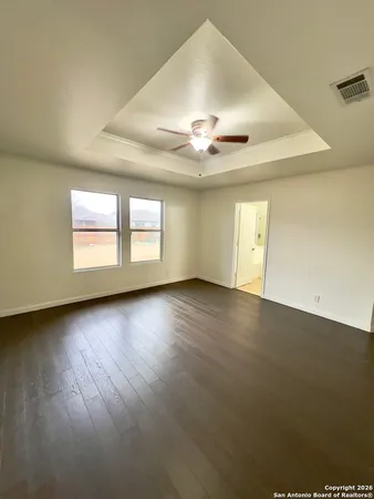 an empty room with wooden floor chandelier fan and windows
