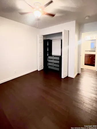 an empty room with wooden floor closet and windows