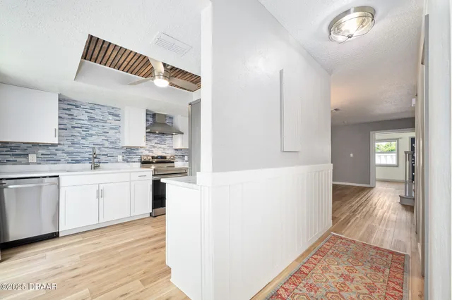 a kitchen that has a lot of white cabinets and wooden floor