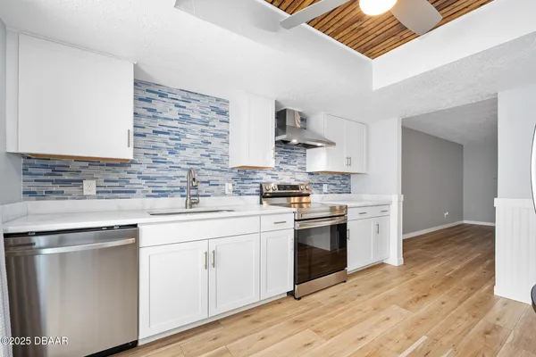a kitchen with stainless steel appliances granite countertop a sink cabinets and wooden floor