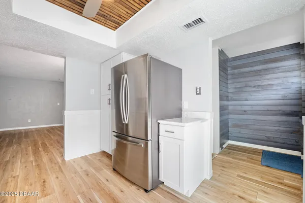 a kitchen with a refrigerator and wooden floor
