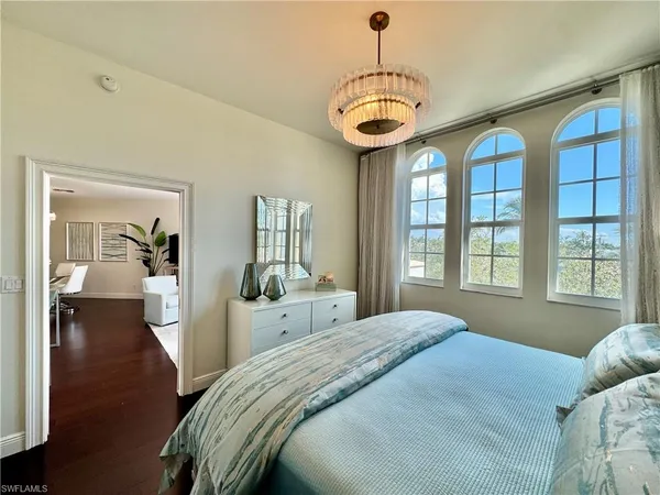 a bedroom with large windows and a chandelier