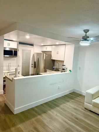 a room with stainless steel appliances wooden floor and view living room