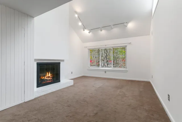 an empty room with windows and fire place
