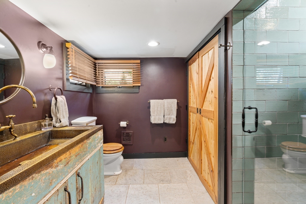 7 Brewer Street, Unit 1 Boston, MA 02130 - Photo 14 of 15 a bathroom with a granite countertop sink a toilet a mirror and shower