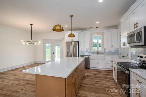 a kitchen with stainless steel appliances granite countertop a sink a stove top oven a counter space and cabinets