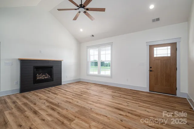 a view of an empty room with window and wooden floor