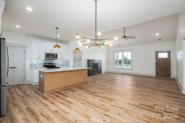 a view of a kitchen with kitchen island wooden floor center island and stainless steel appliances